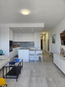 a kitchen and living room with white cabinets and a table at Apartment mit Poolsicht in Costa Del Silencio