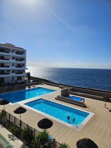 a swimming pool with the ocean in the background at Apartment mit Poolsicht in Costa Del Silencio
