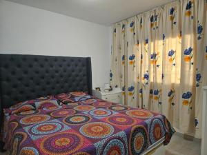 a bedroom with a bed with a colorful comforter and curtains at Apartment mit Poolsicht in Costa Del Silencio +26 photos