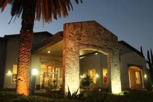 a house with a stone pillar and a palm tree at Howard Johnson Rio Ceballos Hotel y Casino in Río Ceballos