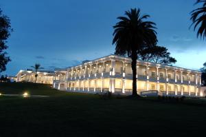 a large building with a palm tree in front of it at Howard Johnson Sierras Hotel y Casino Alta Gracia in Alta Gracia