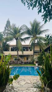 ein Resort mit einem Pool und zwei Palmen in der Unterkunft Resort Brisa in Ilha do Tatu
