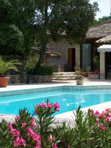 una piscina di fronte a una casa con fiori rosa di Le Verger a Gordes