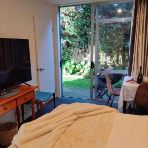 a bedroom with a bed and a desk and a sliding glass door at Whitianga Coastal Stay, Cosy Studio at Oceans Resort in Whitianga