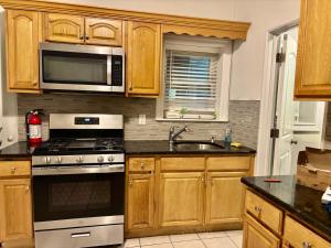 a kitchen with wooden cabinets and a stove and microwave at Penn Station Room Motel Casa in Newark