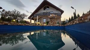 a house with a reflection in a swimming pool at Vila Costi in Câmpina