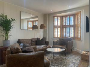 a living room with leather furniture and a mirror at Three Bedroom House in Central Richmond in Richmond upon Thames