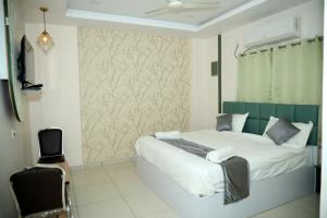 a bedroom with a bed and a chair in it at Hotel Vistaara Grand in Guntūr