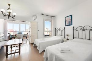 a white room with two beds and a table and chairs at Estudios 79 in Torrox +58 photos