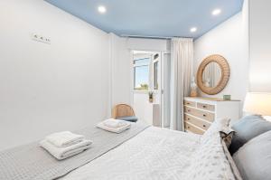 Un dormitorio blanco con una cama y un espejo. en Plazamar 044, en Torre del Mar 12 fotos más