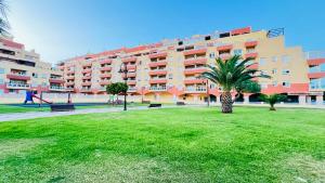 a large apartment building with a palm tree in a park at MAR AZUL Playa y Piscina 80 metros de la playa in Roquetas de Mar