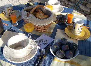 un tavolo con piatti e tazze e un cesto di cibo di Le Verger a Gordes