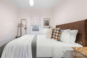 a bedroom with a large bed with white sheets and pillows at Journeyman's Cottage in Ballarat