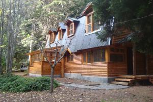 una cabaña de madera en el bosque con un árbol en Cabañas Lucero del Bosque en San Carlos de Bariloche