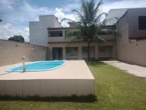 a swimming pool in front of a house with a palm tree at Casa Faé in Guarapari