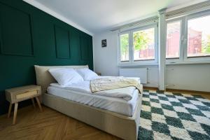 Un dormitorio con una cama con una pared verde. en Apartament 500 metrów do zamku 2, en Malbork