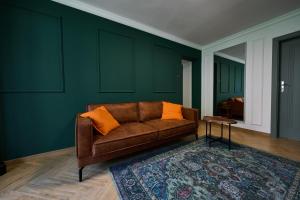 Sofá marrón en una habitación con paredes verdes en Apartament 500 metrów do zamku 2, en Malbork