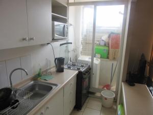 a small kitchen with a sink and a stove at Cuatro Esquinas a pasos de Playa Serena in La Serena