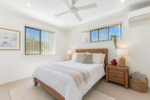 a white bedroom with a bed and two windows at Carseldine Grove in Brisbane