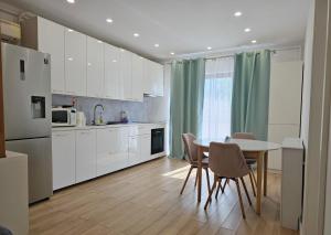 a kitchen with white cabinets and a table and chairs at Apartament Cetății in Floreşti