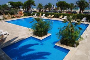 einen großen blauen Pool mit Stühlen und Palmen in der Unterkunft Hotel Costa Verde in Tortoreto Lido