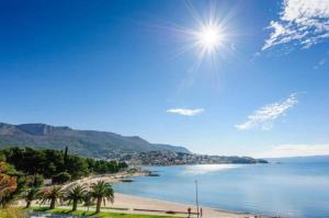 a beach with palm trees and the sun in the sky at Laganini Apartments in Split