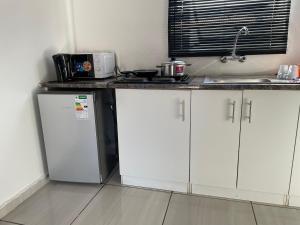 a kitchen with white cabinets and a counter top at Uncle Charles guest house in Pretoria