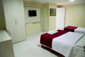 a bedroom with a bed and a bathroom with a tv at Reis Palace Hotel in Petrolina