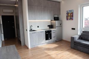une cuisine avec des armoires blanches et un canapé dans une pièce dans l'établissement Sunlit City Loft- Prime Views, à Vilnius 9 autres photos