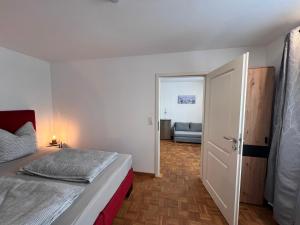 a bedroom with a bed and a door with a couch at Ferienwohnung Scheuring EG in Nordheim
