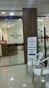a store with two white chairs and a sign at Vila Santa Hotel in Aparecida
