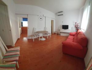a living room with a red couch and a table at GirasolesV in Sanlúcar de Barrameda