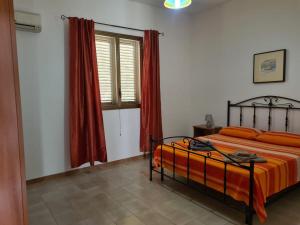 a bedroom with a bed with orange sheets and a window at Casa il Sole Casevacanze Ferienwohnung Daniele Furco in Castellammare del Golfo