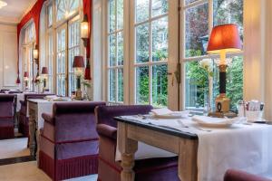 Un restaurante con mesas y sillas y grandes ventanales. en Apollofirst Boutique Hotel, en Ámsterdam
