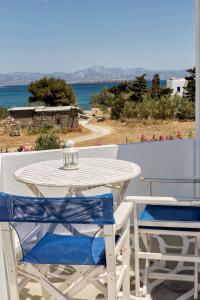 - une table et des chaises blanches sur un balcon donnant sur l'océan dans l'établissement Apartments Tarsa, à Drios