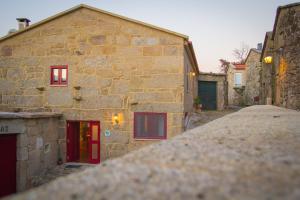 un edificio de piedra con puertas rojas y un callejón de piedra en Casa da Fecha, en Parada