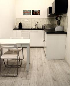 cocina blanca con mesa blanca y sillas en Kiraly Art Apartment, en Budapest