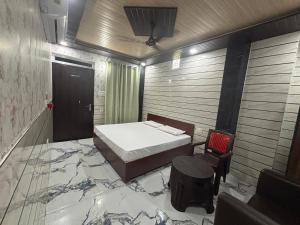 a bedroom with a bed and a chair and a door at Hotel samriddhi palace in Gonda