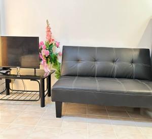 a black couch sitting next to a table with a television at ATVR Juldis Tower Pratunam in Bangkok
