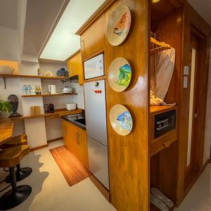 a kitchen with a white refrigerator and wooden cabinets at Aqua Horizon Art Studio Condo in Dauis