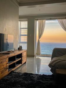 een slaapkamer met een televisie en uitzicht op de oceaan bij AA Sea View in Durban