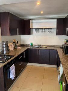 een keuken met donkerbruine kasten en een spoelbak bij AA Sea View in Durban