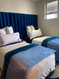 een kamer met twee bedden en een blauw hoofdeinde bij AA Sea View in Durban