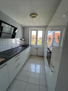 La cuisine est équipée de placards blancs, d'un évier et de fenêtres. dans l'établissement Apartment Lara, à Friedrichshafen