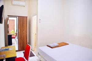 una camera con due letti e una sedia rossa di Urbanview at Nalaya Homestay Mataram a Tjakranegara