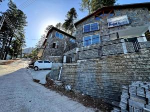 Haven Lodge Khaira Gali - Pine Ridge Residences #4 في Khaira Gali: سيارة بيضاء متوقفة أمام مبنى من الطوب