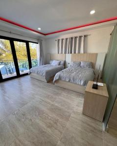 Un dormitorio con dos camas y una mesa y ventanas. en villas el guano, en Sosúa