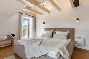 - une chambre dotée d'un grand lit avec des draps blancs et une fenêtre dans l'établissement Luxus-Ferienhaus DS11, à Fehmarn