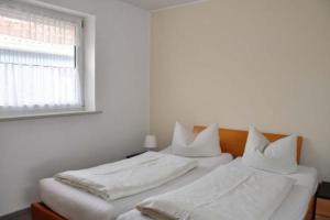 two beds in a white room with a window at Seestern - Wassernah mit Garten und eingezäunter Terrasse in Gollendorf