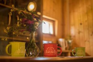 a vase with flowers sitting on a table with two cups at Koryciński wiatrak in Korycin
